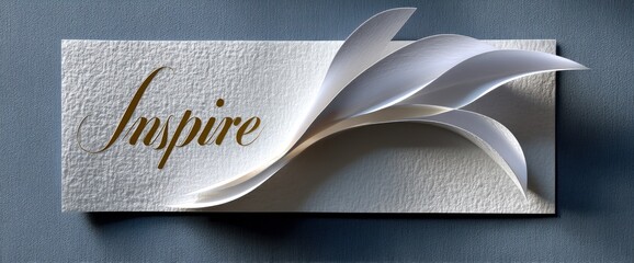 Elegant white paper art with the word "Inspire" in gold script