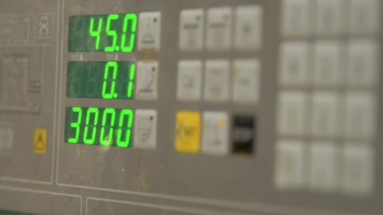 Complex digital control panel with illuminated display and buttons showing various data and readings inside an industrial work area and laboratory - Powered by Adobe