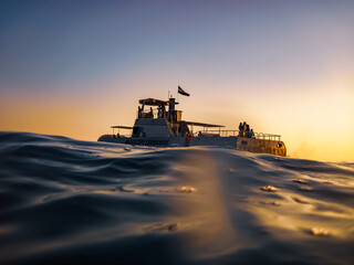 Sightseeing boat at sunset – ocean surface view with warm golden light and peaceful sea
