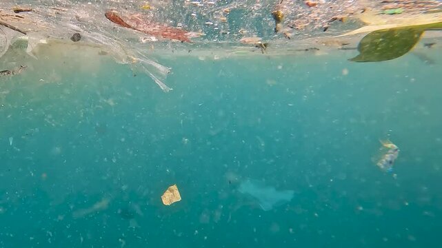 Single use plastic, trash, and debris pollution floating near surface of ocean drifting in currents in tropical island destination of Southeast Asia