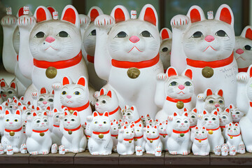 Tokyo, Japan - Sep 30 2024, A close-up view of many multi-sized white beckoning cat figure of Maneki neko with red ears and noses displayed at Gotokuji Temple, without people, at daytime, Tokyo, Japan