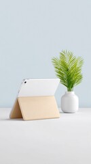 White Tablet in Beige Keyboard Folio Stand on White Desk with Green Plant