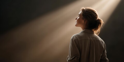 businesswoman career goal-setting. A woman in a dimly lit space, illuminated by soft beams of light.