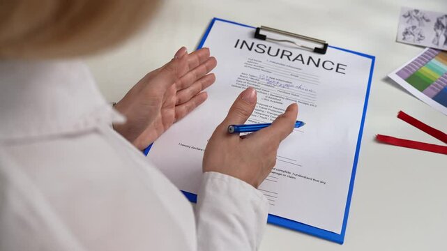 Person Signing an Insurance Document with a Blue Pen