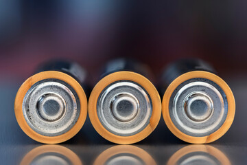 Close-up of AA alkaline batteries lying down with a blurred industrial background