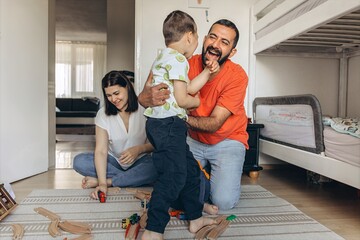 Parents playing and laughing with their two sons in a bright children room. Family bonding, playful...