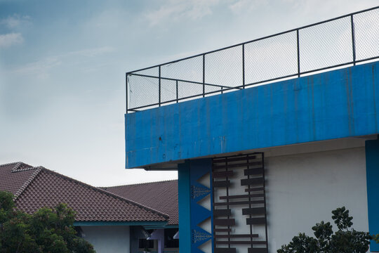 Blue Building Corner With Rooftop Fence and Concrete Detail - Powered by Adobe