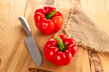 Sweet red peppers with home accessories on a wooden table, close-up.