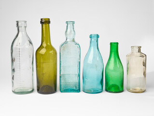 Vintage apothecary glass jars in a row close-up on white background. Antique colored glassware 