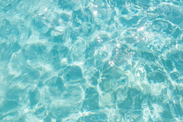 Blue water texture with sunlight sparkles and soft ripples