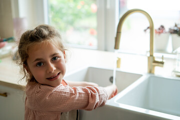 Closeup of children's hands washing a plate near the sink in the kitchen. Eco dishwashing brush.