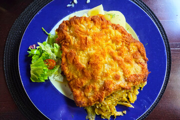 Crispy Breaded Schnitzel with Fresh Salad and Savory Cabbage on a Blue Plate