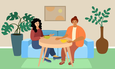 Womens gathering in a cafe or at a party. Two girlfriends are sitting at a table on a blue sofa. They are drinking tea. In the background there is a vase or a pot with a houseplant 