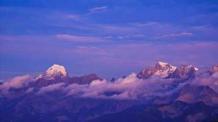 Majestic mountain peaks illuminated by soft twilight colors showcasing the serene beauty of nature against a cloudy sky