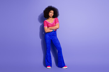 Stylish young woman in vibrant outfit posing against a purple background, expressing confidence and...