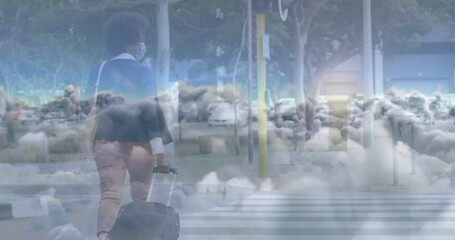 Image of clouds over african american businesswoman walking