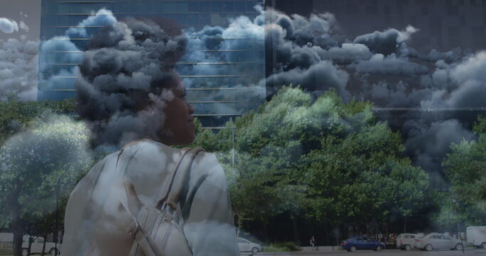 Image of clouds over african american businesswoman walking