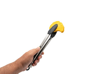 Hand holding kitchen tongs with a breaded schnitzel, isolated on white background. Demonstrates practical food handling.