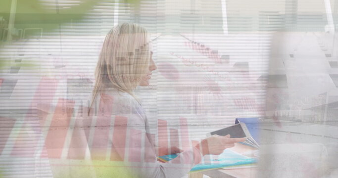 Image of caucasian businesswoman working at desk over graphs