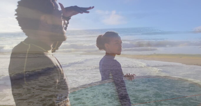 Image of sea over african american couple with surfboards at beach