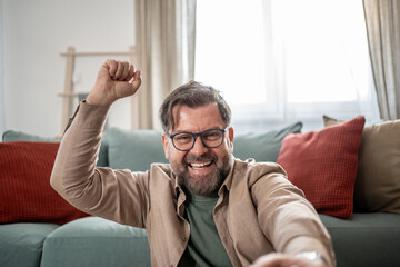 Fototapeta premium Excited man celebrating success at home raising fist
