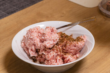Just ground meat mince in the glass bawl of the electrical chopper on the kitchen counter top being seasoned and mixed. Cooking