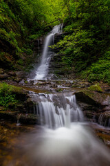 Waterfall in the mountains, river rapids, fast flow, Scenic view of pristine Carpathian nature with crystal clear water cascading over mossy rocks. Photo wallpaper, beauty of nature and the Earth.