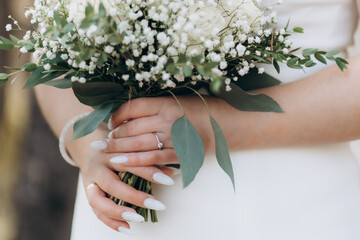 Beautiful bride holds white bouquet. Bouquet of white rosses in woman's hands.