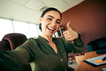 Confident businesswoman in an office giving a thumbs up gesture, embodying success, positivity, and...