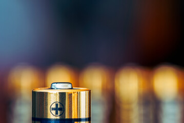 Close-up of AA alkaline battery standing upright with a blurred industrial background