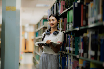 A female student is browsing books on a shelf in the library, focused on finding the right material for her studies.