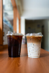 Take home cup with iced black coffee and iced latte on wood table