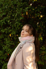Pretty young girl wearing light coat in the autumn park