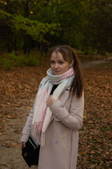 Pretty young girl wearing light coat in the autumn park