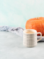 Pumpkin spiced latte coffee on turquoise background with orange squash