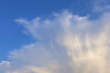 A massive cumulus cloud is a harbinger of an approaching storm against a blue sky. Rainy weather.