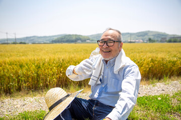 休憩する農家の男性、日本人シニア、水分補給
