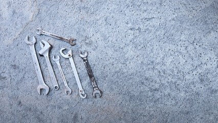 Professional tools and wrenches scattered on concrete surface, preparing for automotive repair. Copy space