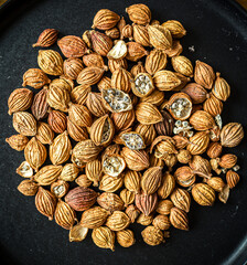 A close-up, top-down view of dried black cardamom pods on a dark surface, revealing their aromatic seeds inside.