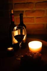 Wine glass and romantic candles at wine cellar covered in old bricks