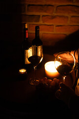 Wine glass and romantic candles at wine cellar covered in old bricks