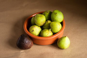 Fresh Green And Ripe Figs in a Clay Bowl on Brown Background
