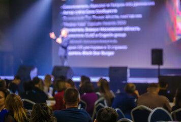 Engaging speaker presenting to attendees in a conference hall with focus on interaction.
