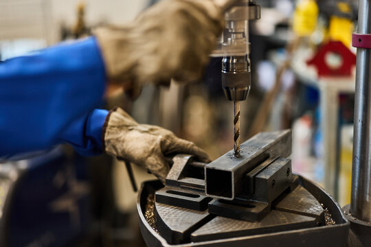 Worker Drilling Metal in Workshop Using Industrial Equipment for Precision Work