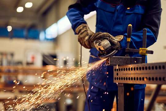 Worker using Power Grinder on Metal with Sparks in Industrial Workshop