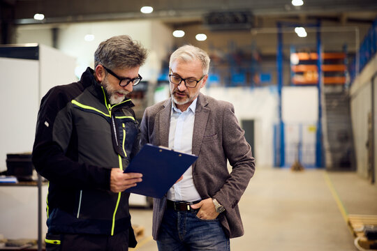 Two Professionals Discussing a Project in a Modern Warehouse Interior