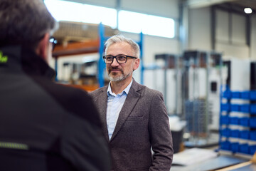 Businessman Communicating In Warehouse Environment During Professional Interaction