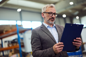 Senior Manager Reviewing Documents in a Modern Industrial Workplace