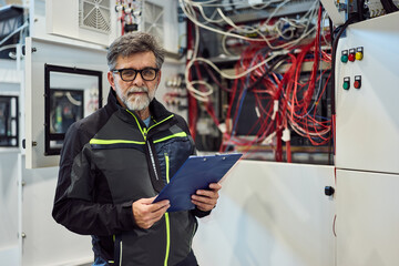 Experienced Technician Inspecting Data Center with Wiring and Equipment