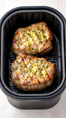 Two seasoned boneless pork chops cooking in an air fryer basket, top view, close-up.